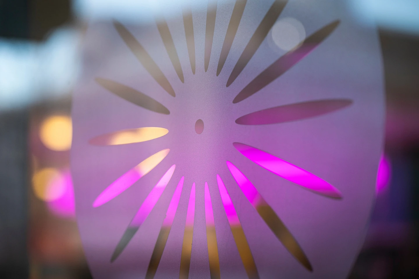 Closeup photo of colored lights shining through the sunburst cutout of a terrace chair at the Memorial Union