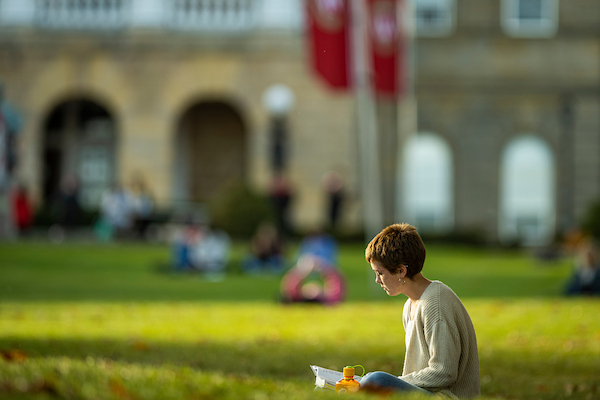 reads a book among the colors of the fall leaves on Bascom Hill