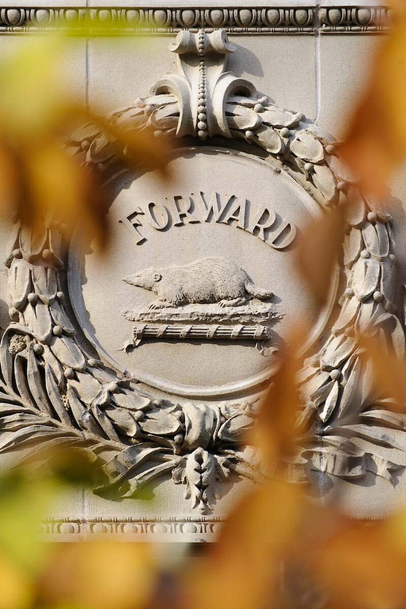 Stone engraving of the state Wisconsin "forward" motto and iconic image of a badger on the exterior of a UW building.