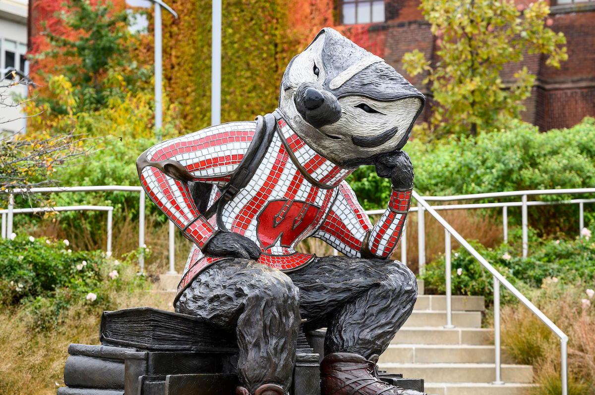Statue of Bucky Badger leaning over his knee with his head resting on a closed fist.