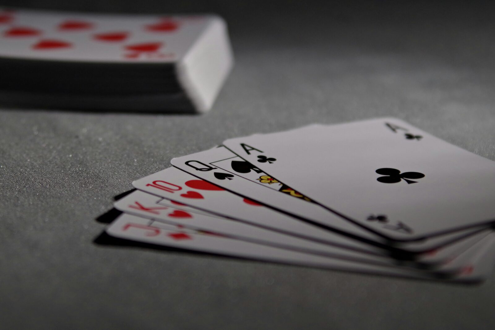 A deck of playing cards is in the background, with a hand of 5 cards is shown