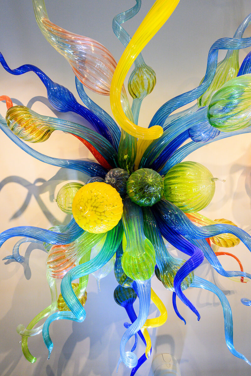 Colorful glass sculpture with curling blue, green, and yellow forms.