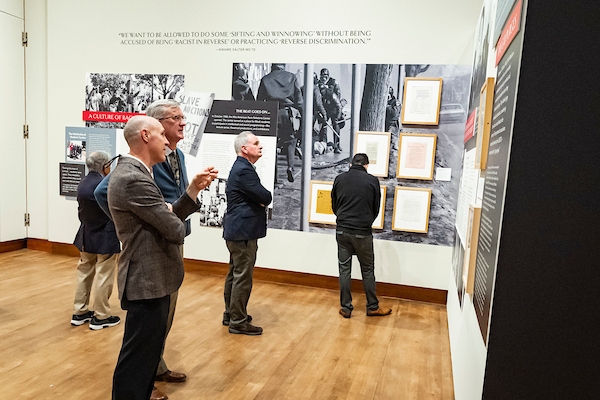 Visitors view large photo panels and framed texts in a gallery exhibit.